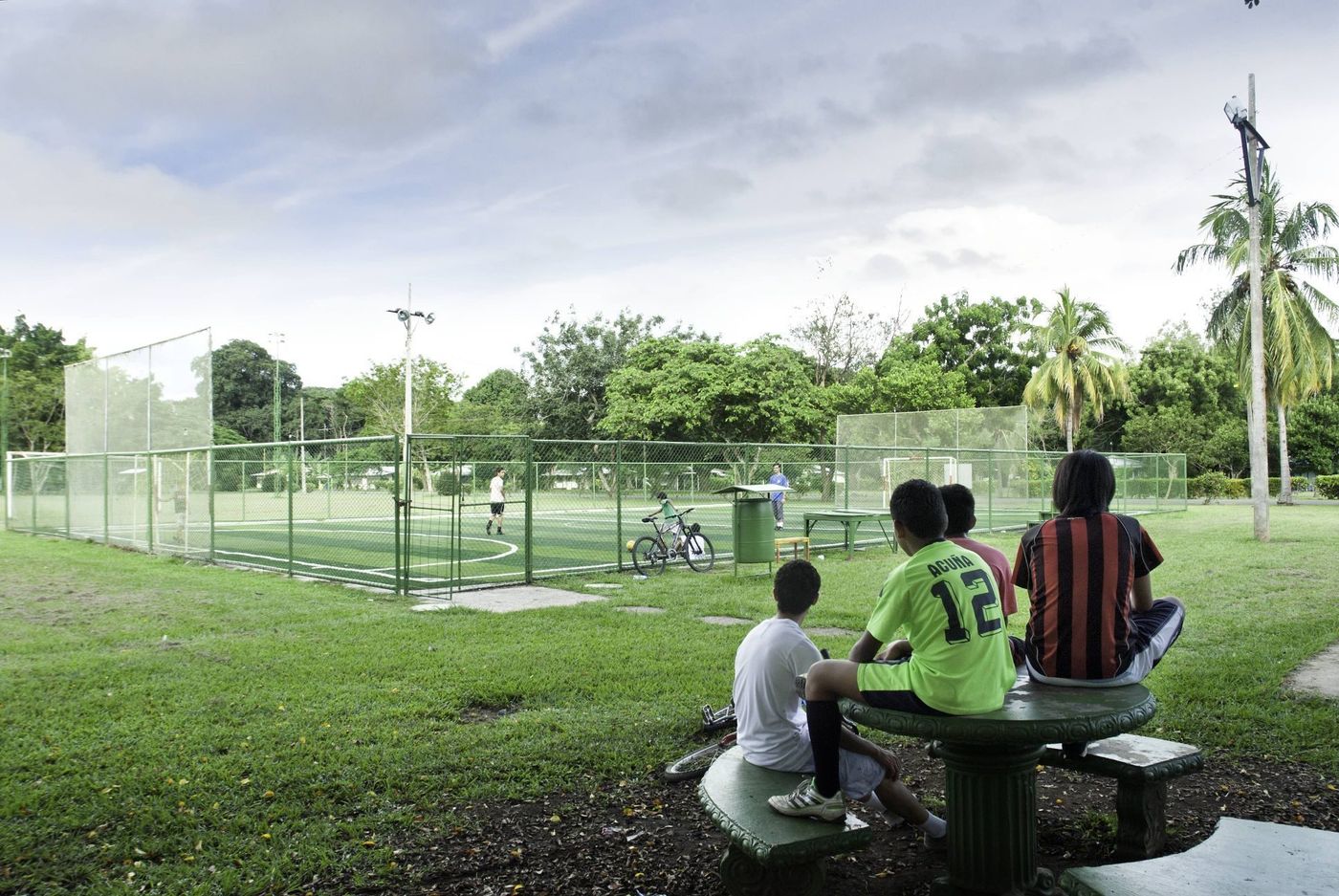 Áreas deportivas de la comunidad con niños descansando bajo la sombra